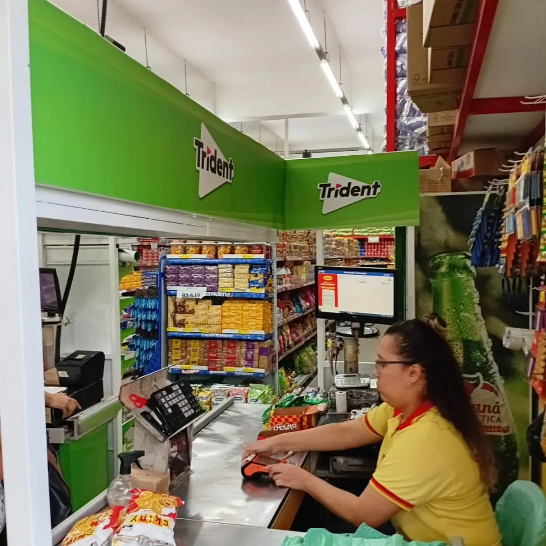 Operadora trabalhando no caixa adesivado com a marca Trident